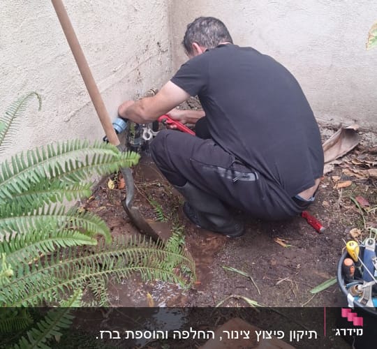 אינסטלטור מתקן צנרת מים בחצר ליד קיר חיצוני